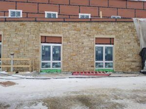 Tan ledger stone veneer installation on a commercial building exterior.